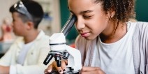 A middle school student looking through a microscope.