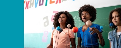 Three female middle school students presenting a project in front of the class